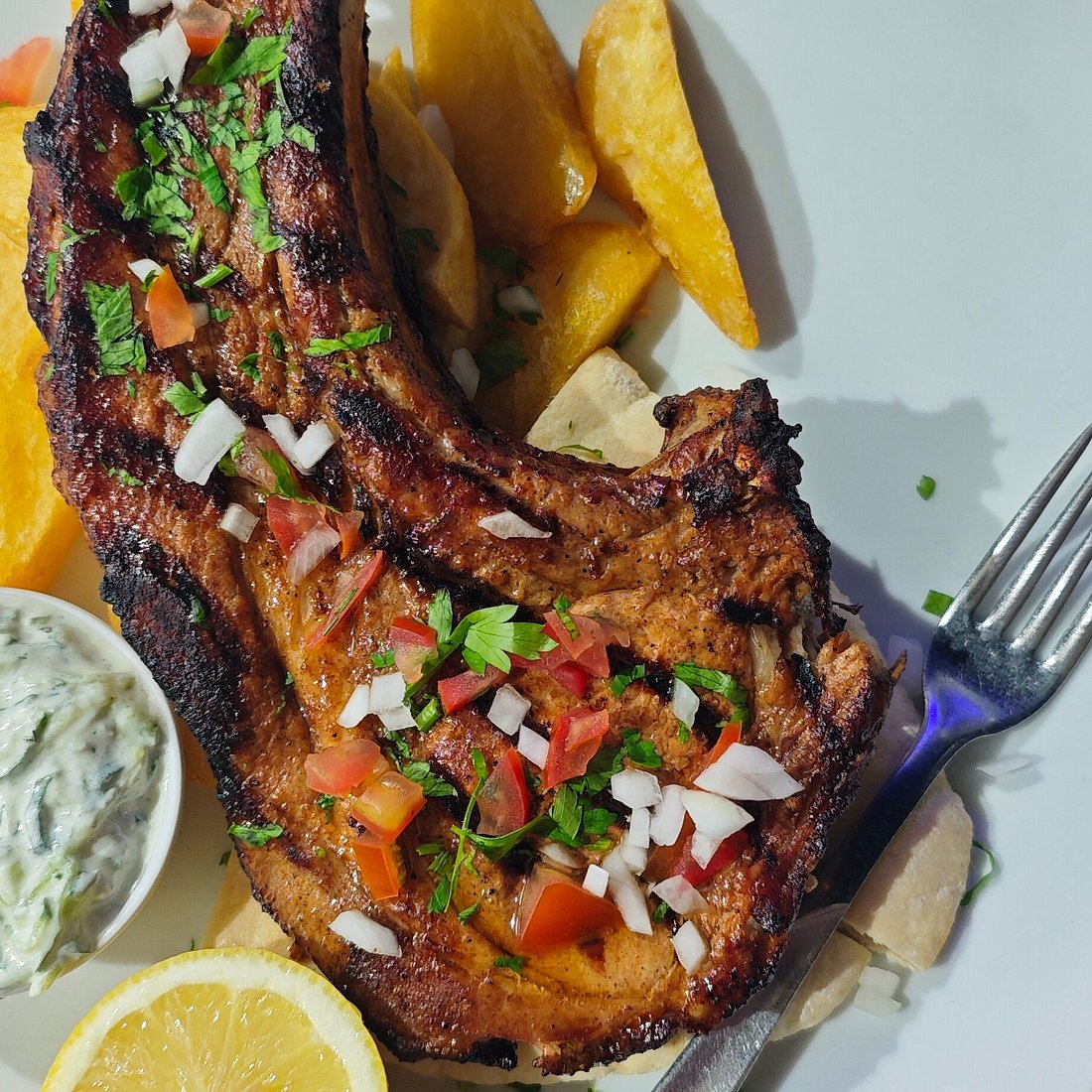 A grilled pork chop with potatoes served at Doma